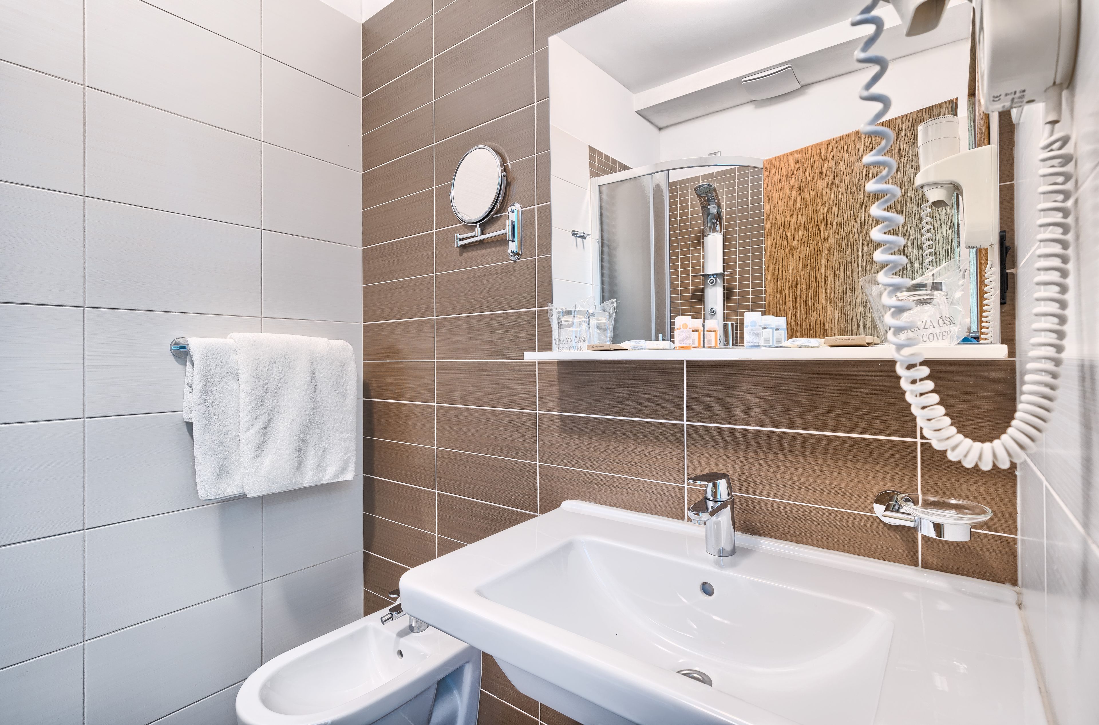 A modern bathroom with a white sink, a mirror, and a towel rack.