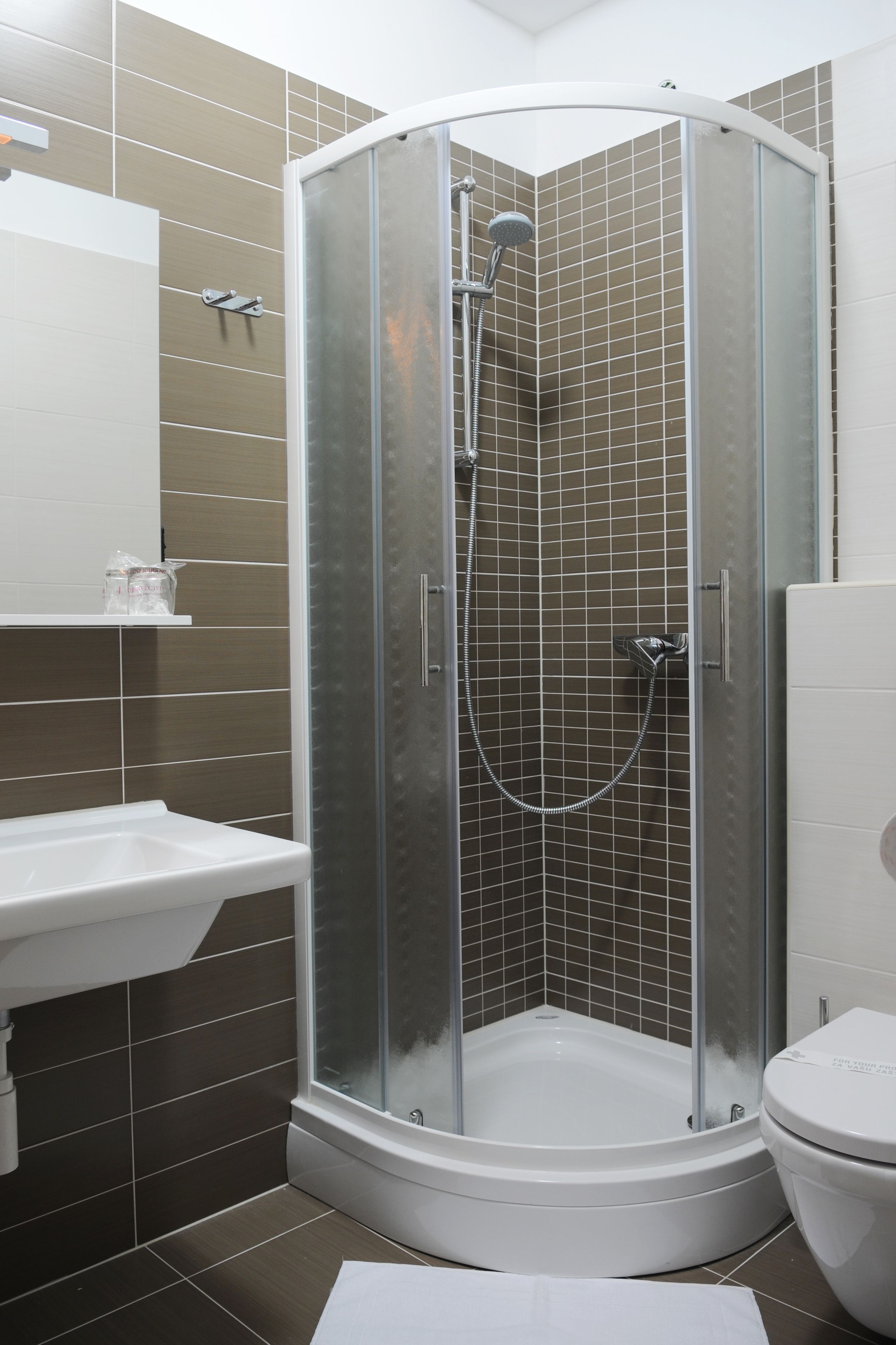 A modern bathroom with a glass-enclosed shower, a white sink, and a toilet.