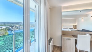 A modern hotel room with a balcony, a bed, a desk, and a chair. - Hotel Panorama (Sibenik)