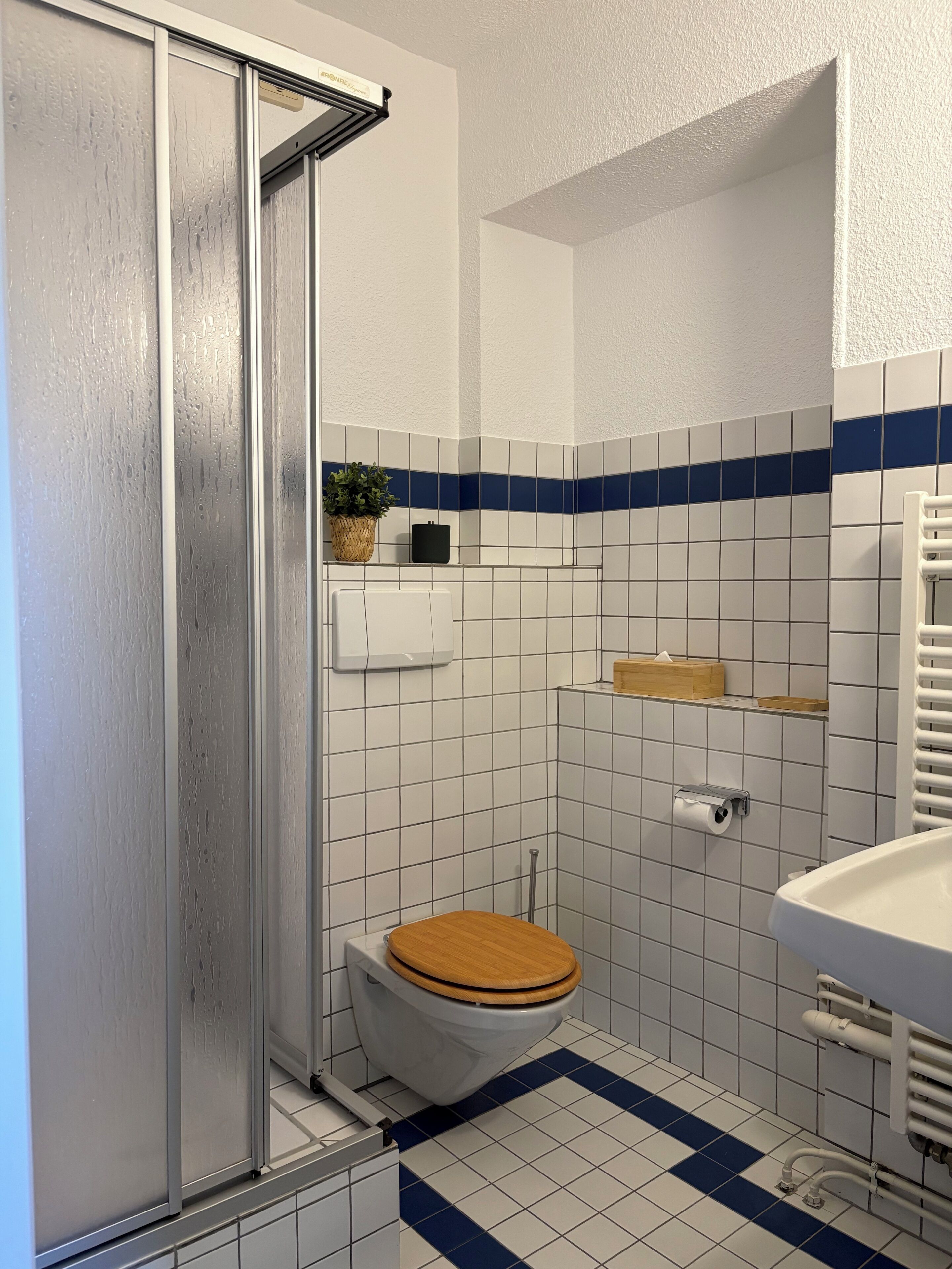 A bathroom with a shower, toilet, sink, and tiled walls.