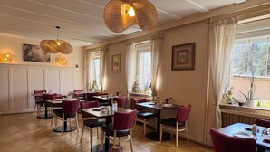 A dining area with wooden flooring, red upholstered chairs, and tables set for dining. - Hotel Deybach (Munster)