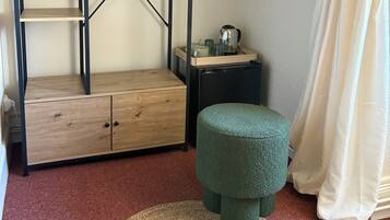 A room with a bunk bed, a small desk, a green ottoman, and a round woven rug.