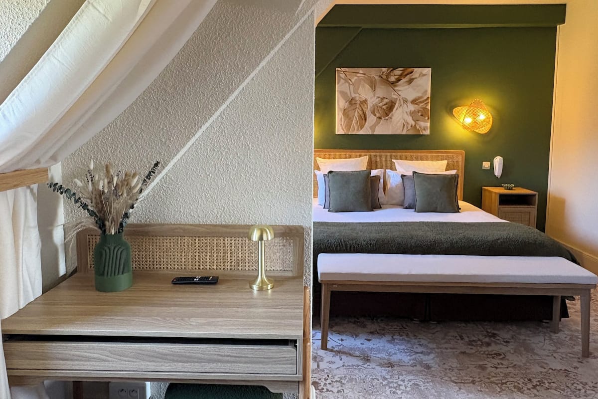A bedroom with a bed, bedside table, lamp, and a painting on the wall.