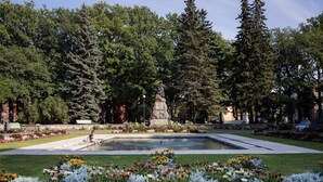 A park with a statue, a fountain, and a variety of flowers. - Koidulapark Hotell (Parnu)