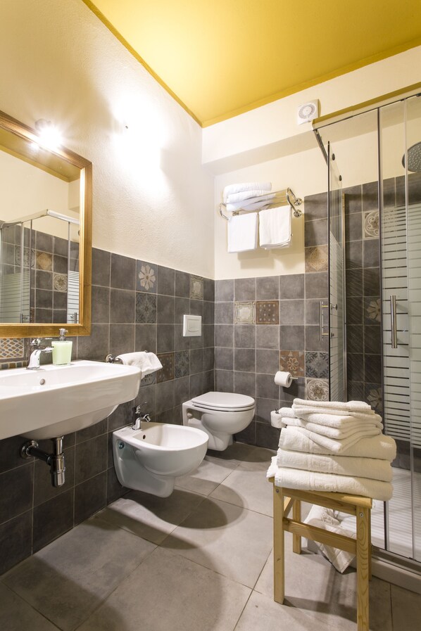 A bathroom with a sink, bidet, toilet, and a glass-enclosed shower area. - Villa Asfodeli (Tresnuraghes)