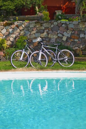 A bicycle parked by a stone wall near a swimming pool. - Villa Asfodeli (Tresnuraghes)