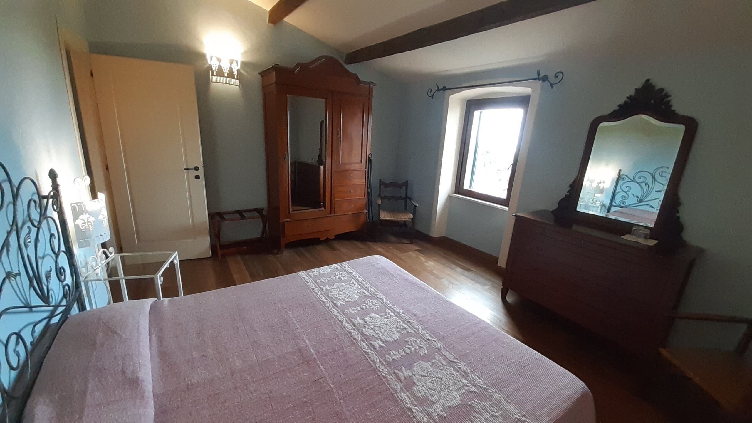 Una camera da letto con un letto, un'armadio in legno e uno specchio.