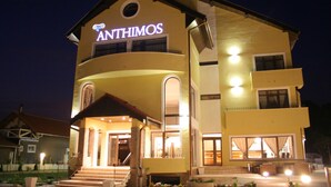 Un bâtiment à deux étages, sur lequel on peut lire l’inscription « ANTHIMOS » en haut.