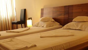 Ein Hotelzimmer mit zwei Einzelbetten, einem Holzkopfteil, einem Sessel und einer Lampe.