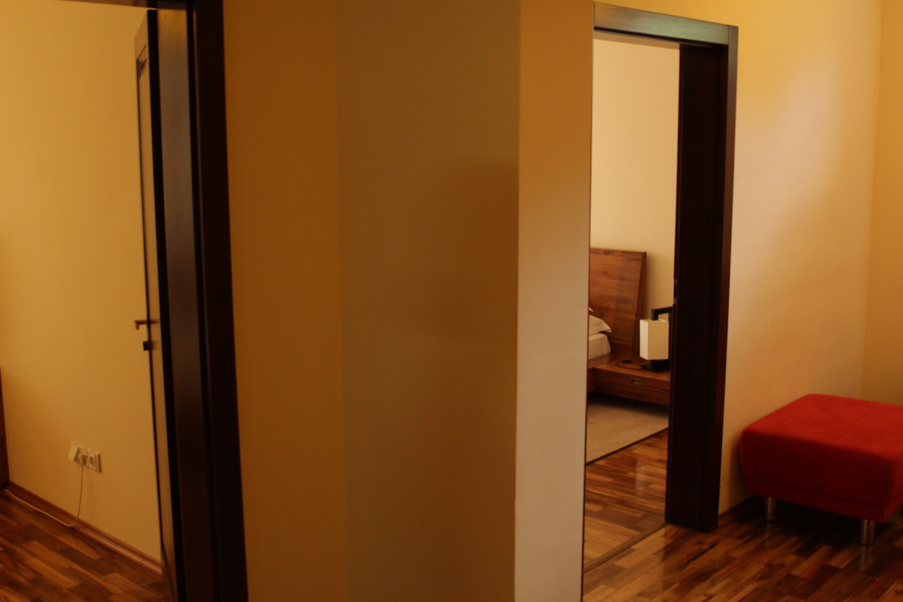 A hallway with wooden flooring, a red bench, and a door leading to another room.