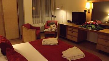 A hotel room with a bed, a desk, a chair, a television, and a mirror.