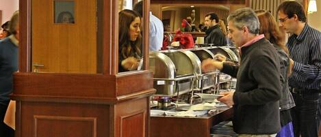 Un espace buffet doté de plusieurs points de service, d’un pilier en bois et d’un miroir qui reflète la pièce.