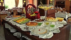 A buffet setup with various dishes, including a fruit bowl, a martini glass, and a variety of platters. - Palace Hotel & Spa Termas de São Vicente (Penafiel)