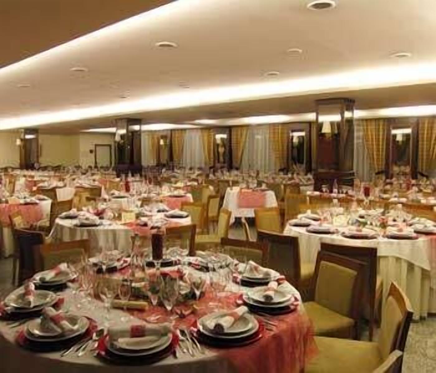 A banquet hall with round tables set for dining, featuring multiple chairs and tables arranged in rows.