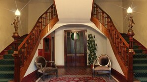 A grand staircase with wooden railings and a red carpet leading to a door. - Palace Hotel & Spa Termas de São Vicente (Penafiel)