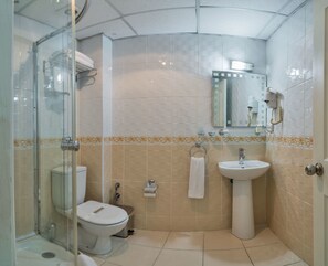 A bathroom with a glass-enclosed shower, a toilet, a sink, and a mirror. - May Hotel (Istanbul)