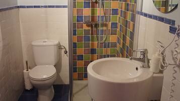 A bathroom with a shower, toilet, sink, and a mirror.