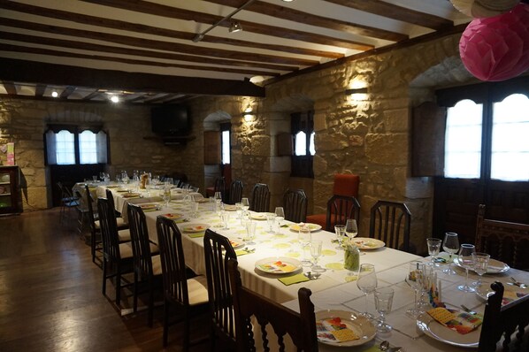 A long dining table set with chairs, surrounded by stone walls and wooden beams. - Arganzón Plaza (La Puebla De Arganzon)