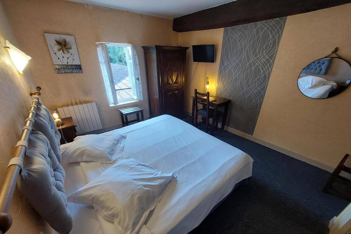 Une chambre d’hôtel avec un lit, un bureau, une chaise, une télévision et une fenêtre.