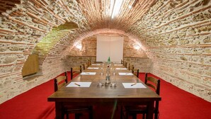 A long table with chairs, set in a stone-walled room with a red carpet. - La Table d'Antan (Bon-Encontre)