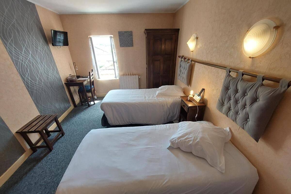 Une chambre d’hôtel avec deux lits, un bureau, une chaise, une télévision et une fenêtre.