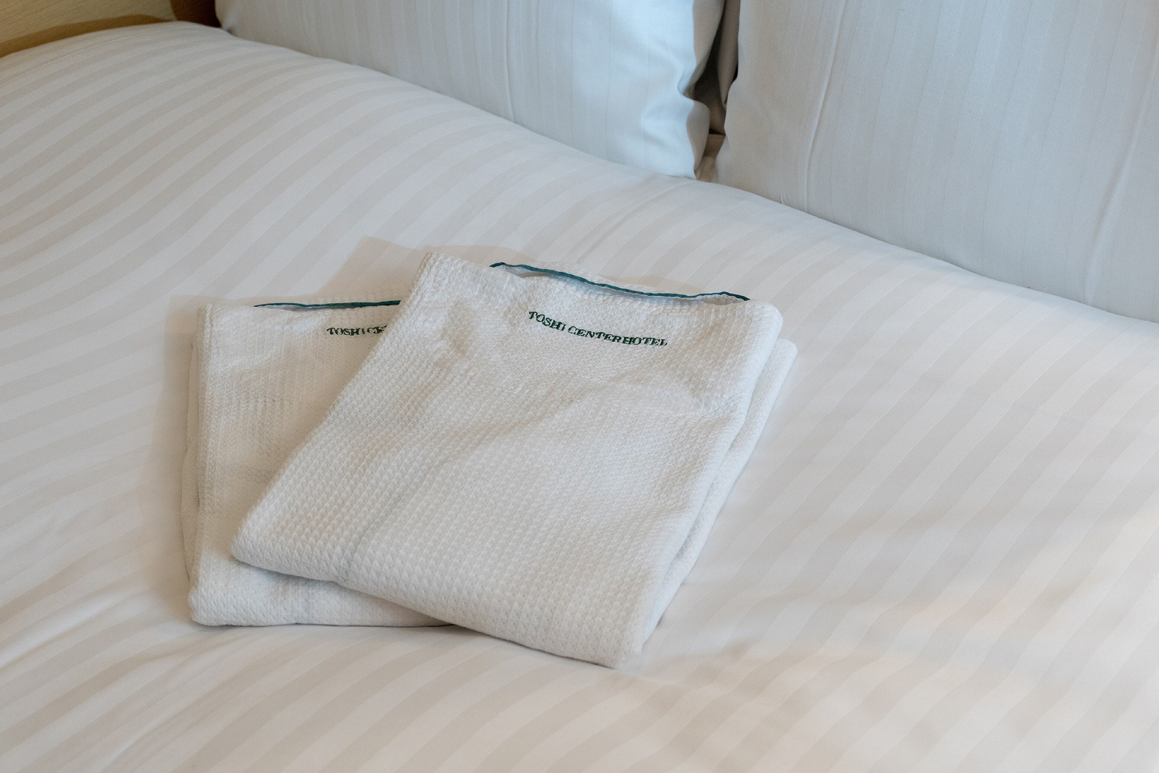 Un letto rifatto con due asciugamani con la scritta 'TOSHICENTERHOTEL'.