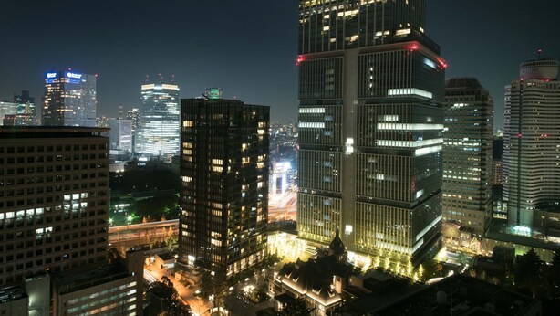 A nighttime cityscape with modern high-rise buildings, illuminated windows, and a busy street below. - Toshi Center Hotel Tokyo (Tokyo)