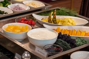 Un buffet proposant une variété de plats, notamment des fruits, des légumes et un bol de soupe.