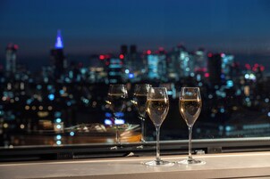 Three champagne flutes on a table with a cityscape view in the background.