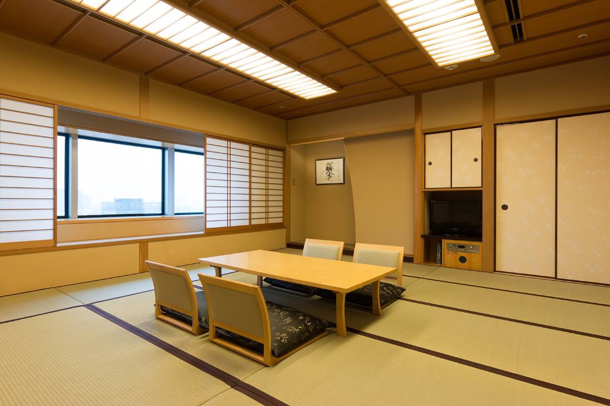 A traditional Japanese room with tatami flooring, a low table with cushions, and sliding doors.