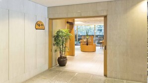 A reception area with a potted plant, a wooden sign, and a seating area with chairs and a table. - Toshi Center Hotel Tokyo (Tokyo)