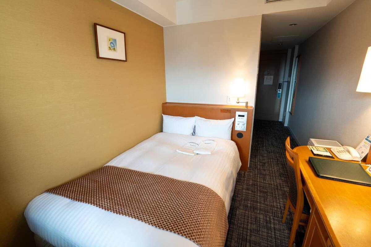 A hotel room with a bed, a desk, and a chair.