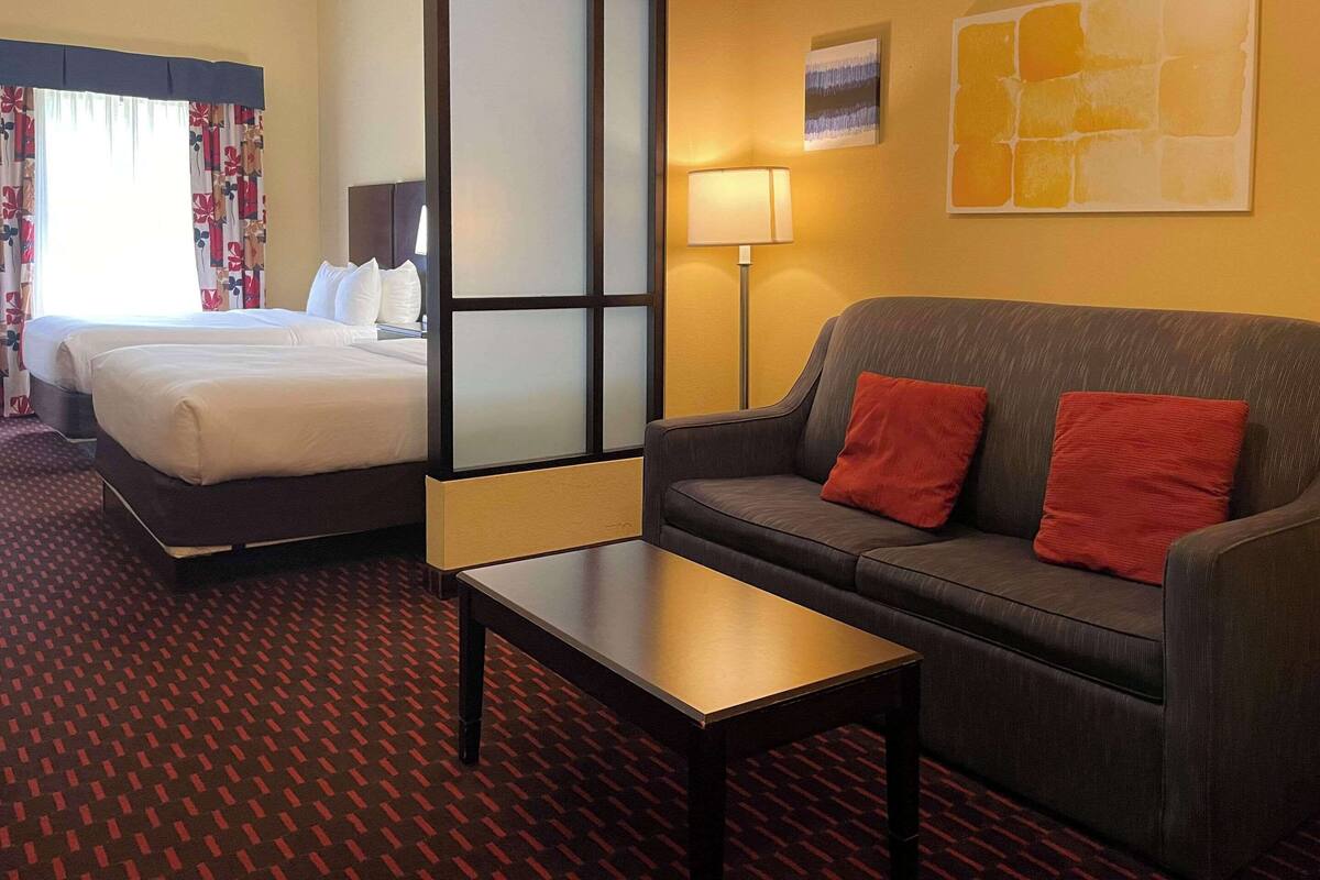 Ein Hotelzimmer mit einem Bett, einer Couch, einem kleinen Tisch und einer Lampe.
