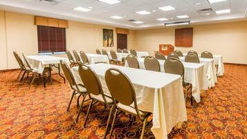 A conference room with multiple tables and chairs, carpeted floor, and ceiling lights.