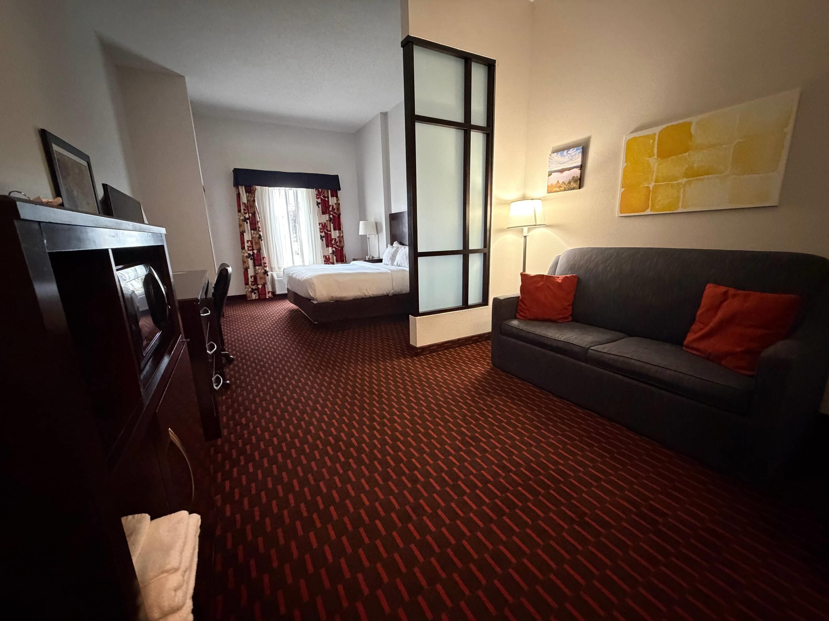 Una habitación de hotel con cama, sofá, escritorio y televisor.