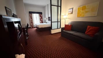 Una habitación de hotel con cama, sofá, escritorio y televisor.