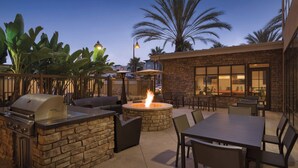 Un patio al aire libre con una parrilla de piedra, un hogar para fuego y asientos.