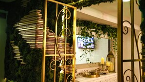A room with a bookshelf, a TV, and a decorative wall with plants. - Casa Victoria Orchid (Miami Beach)