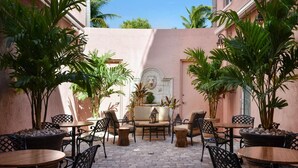 An outdoor patio with tables and chairs, surrounded by potted plants and a decorative wall. - Casa Victoria Orchid (Miami Beach)