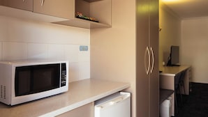 A compact kitchenette with a microwave, a small refrigerator, and a sink.