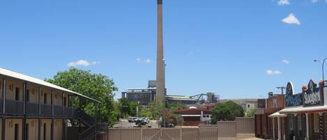 Una extensa zona industrial con una chimenea alta, un estacionamiento cerrado y edificios con señalización.
