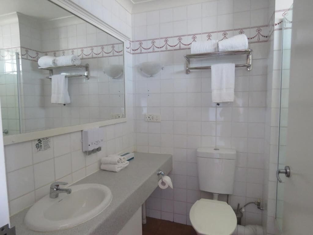 A bathroom with a sink, toilet, and a shower area.