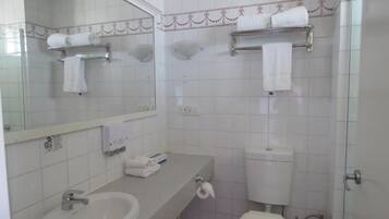 A bathroom with a sink, toilet, and a shower area.