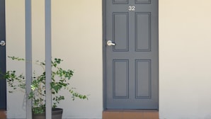 A gray door with the number 32, a potted plant to the left, and a window above the door.