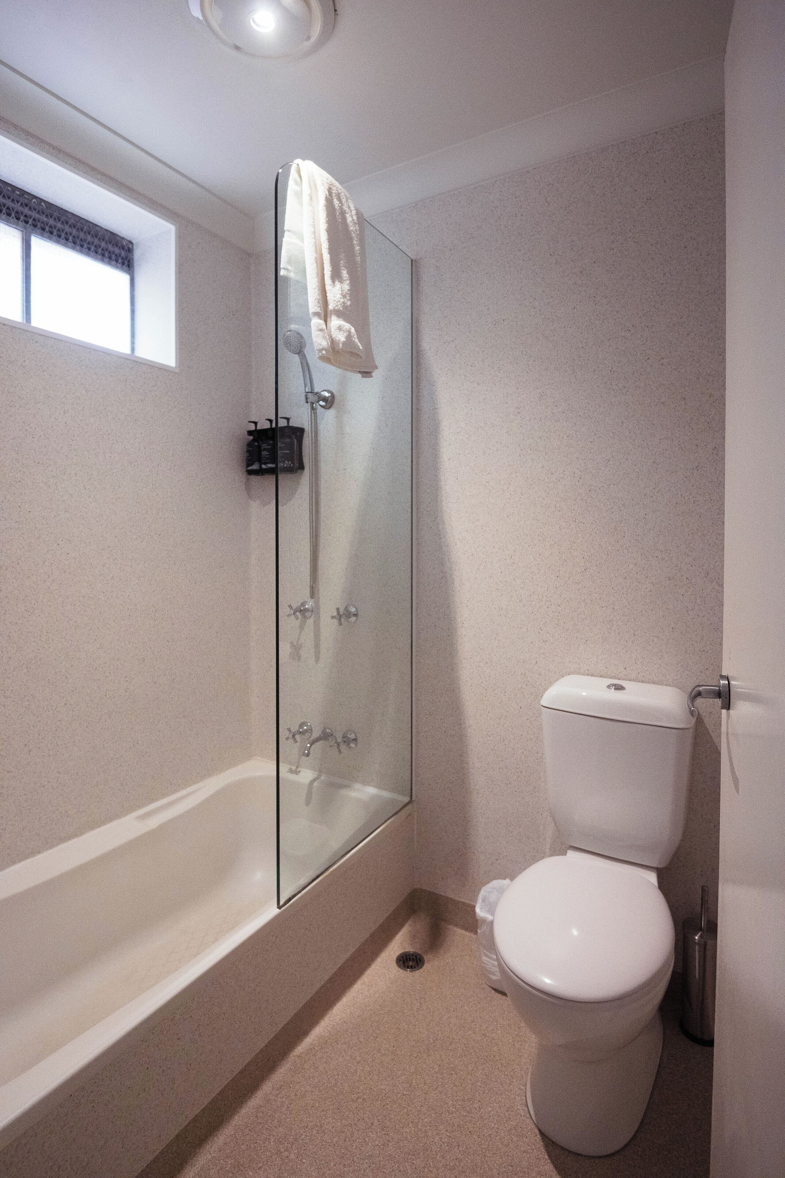A modern bathroom with a glass-enclosed shower, a white toilet, and a bathtub.