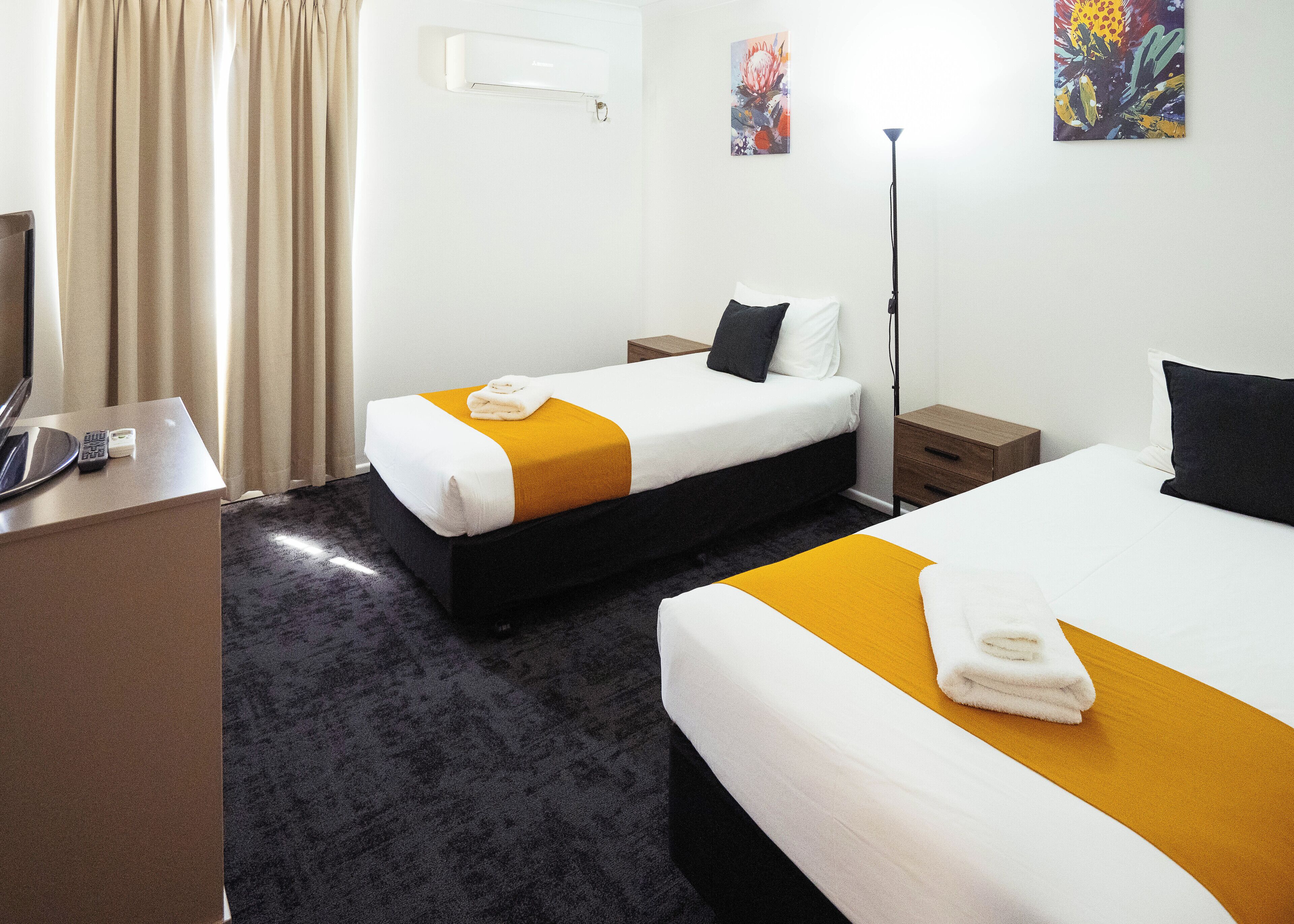 Habitación de hotel con dos camas, un escritorio y una silla.