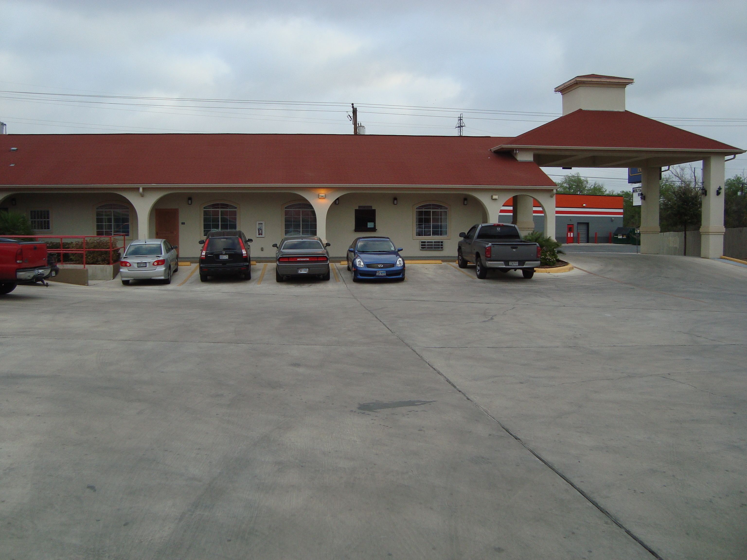 A building with a red roof and a parking lot with five cars.