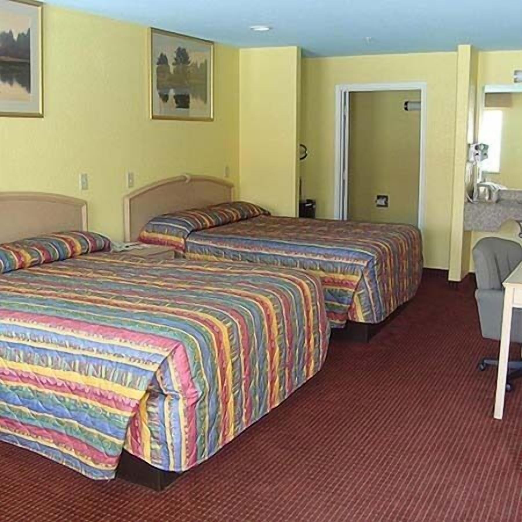 A hotel room with two beds, a desk, and a chair.