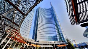 A modern building with a curved glass facade and a prominent spire. - Holiday Inn Milan Nord Zara by IHG (Cinisello Balsamo)