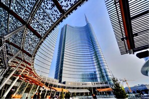 A modern building with a curved glass facade and a prominent spire. - Holiday Inn Milan Nord Zara by IHG (Cinisello Balsamo)